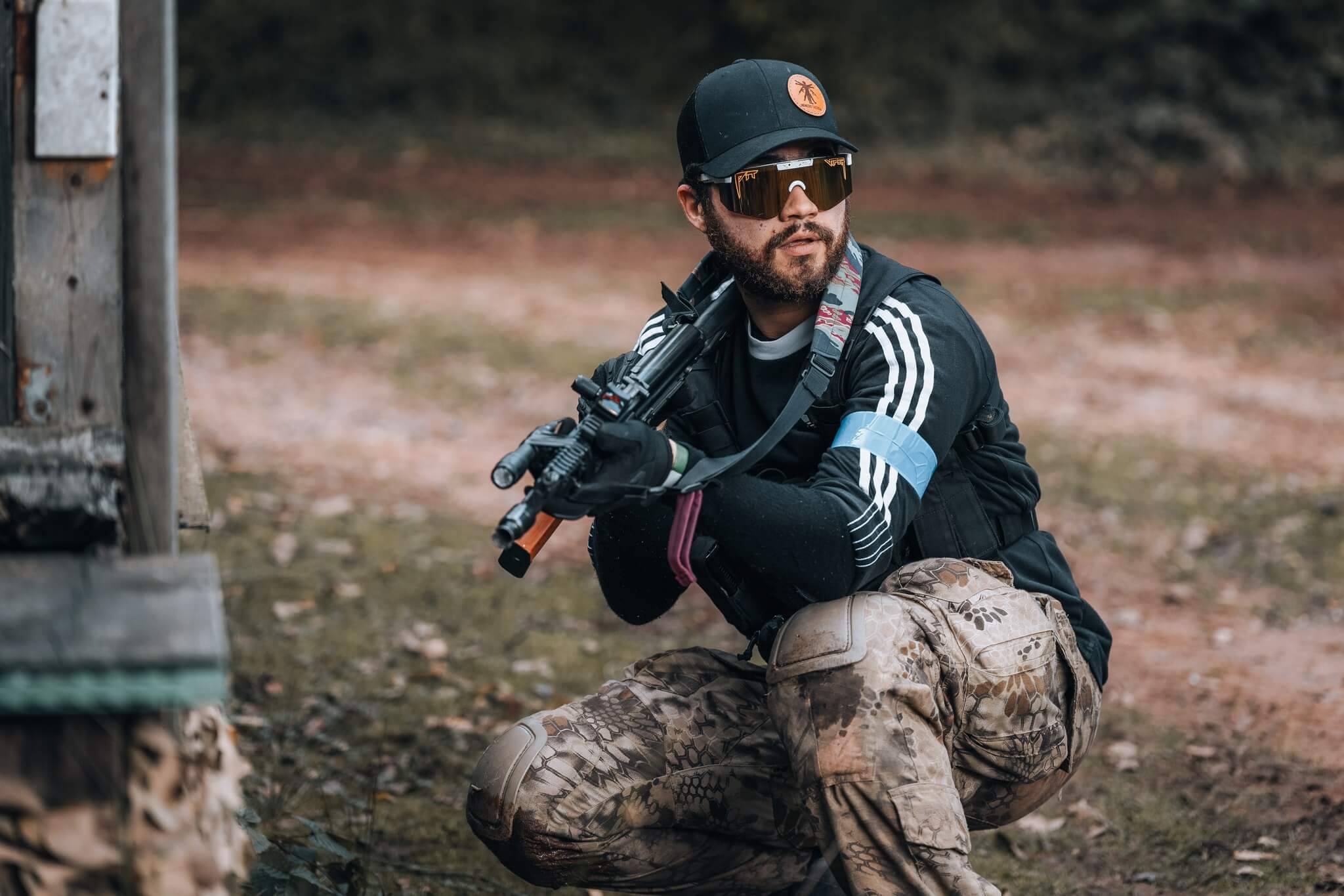 Airsoft player aiming from cover with an AK rifle